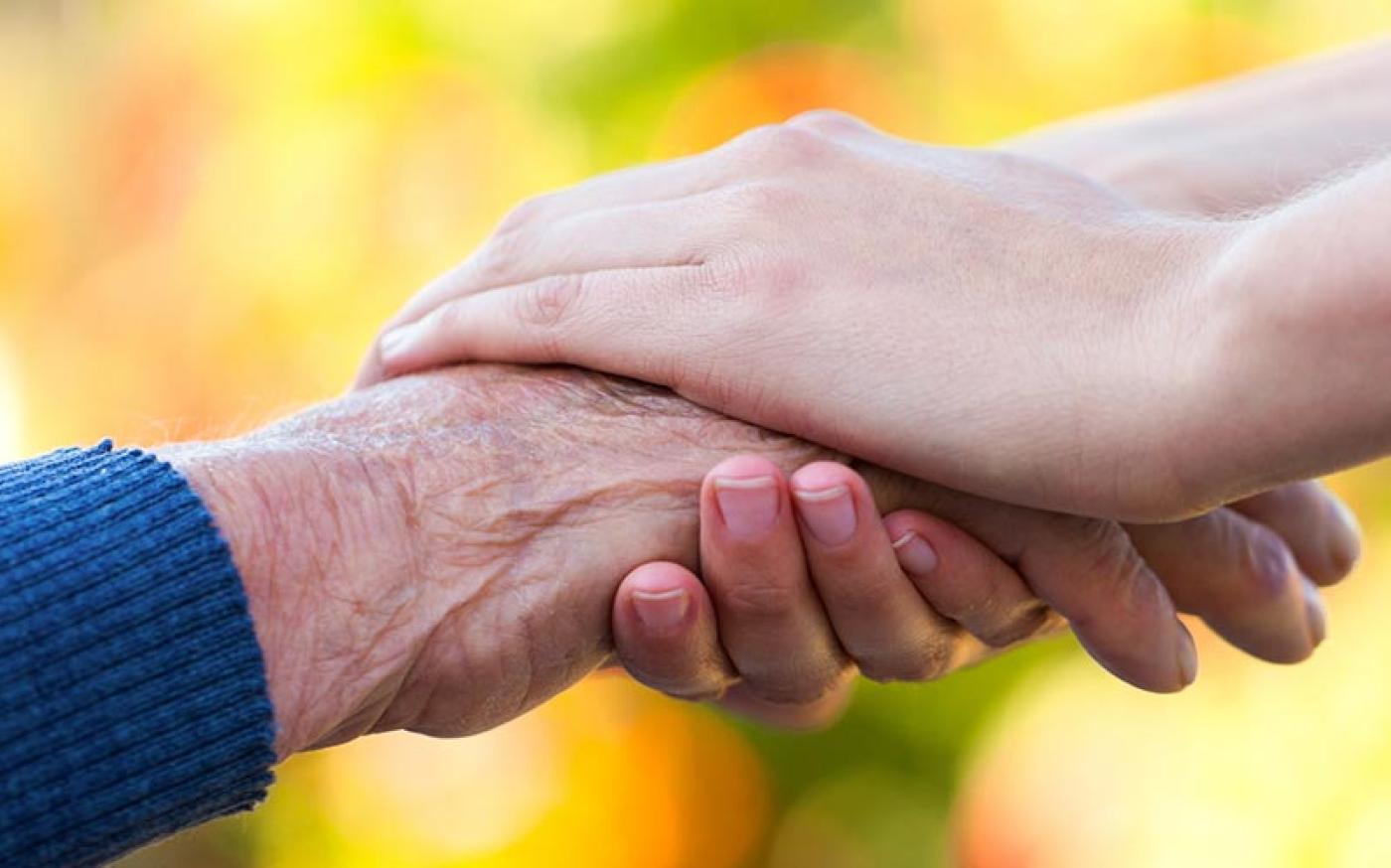 Close-up image of an elderly hand being held by a younger-looking hand