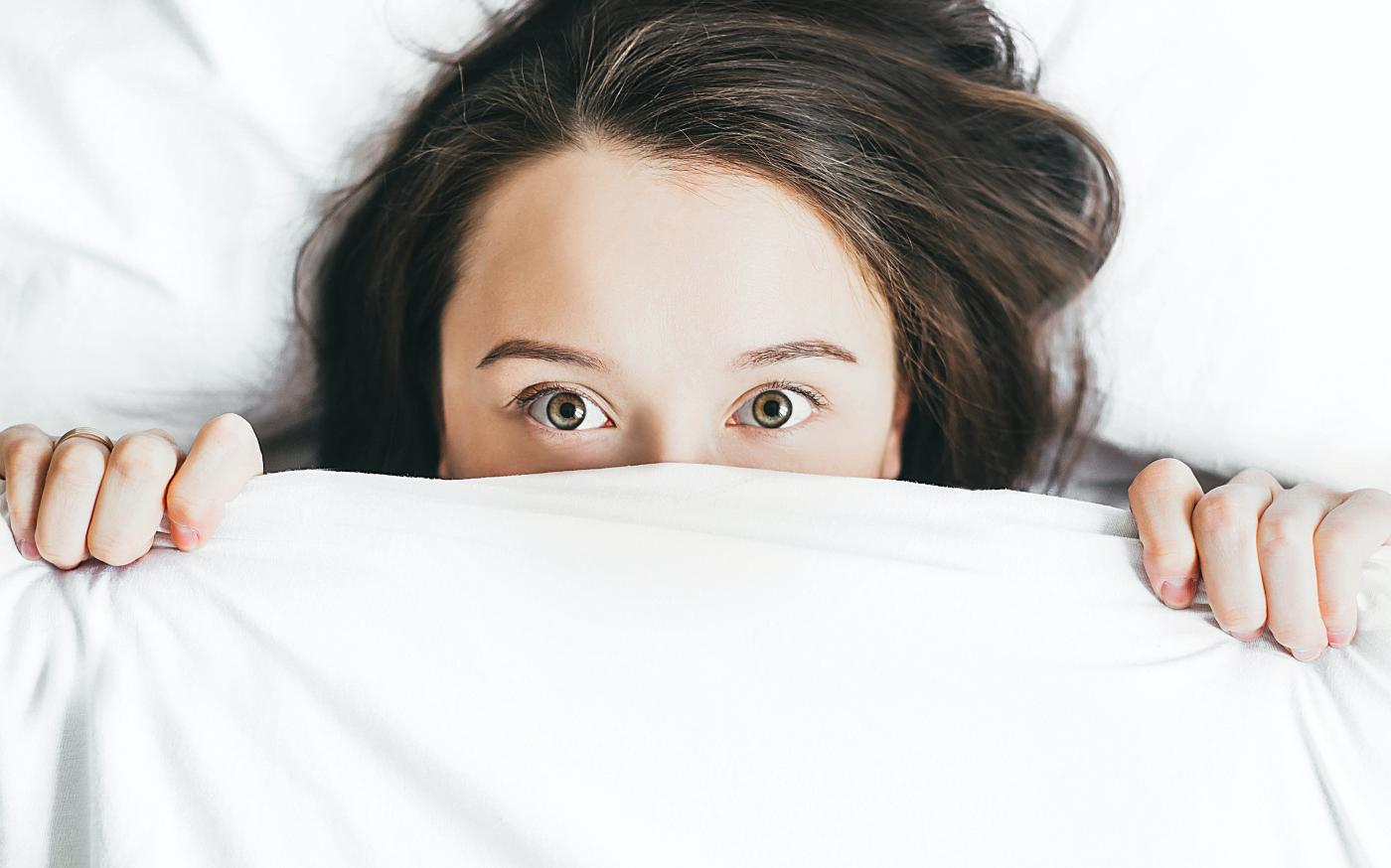 woman covering her face with blanket by Alexandra Gorn courtesy of Unsplash.