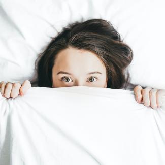 woman covering her face with blanket by Alexandra Gorn courtesy of Unsplash.